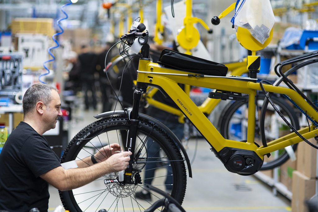 Assembler at bicycle wheel in yellow hanger