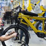 Assembler at bicycle wheel in yellow hanger